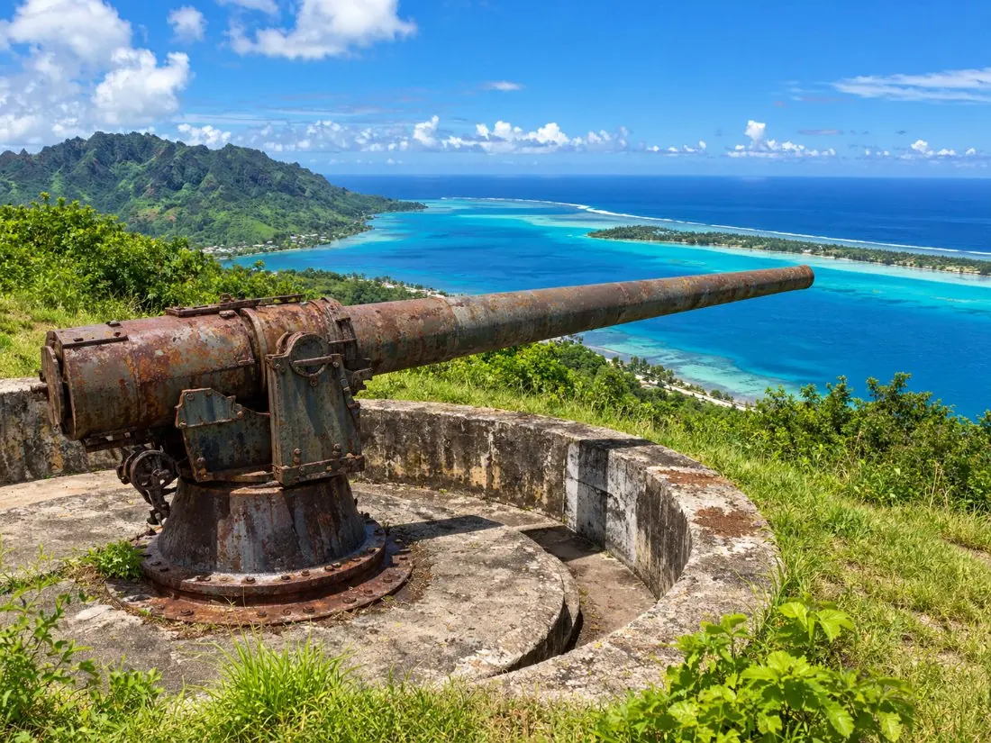 An old WWII coastal cannon on a green hillside lookout above the Bora Bora lagoon